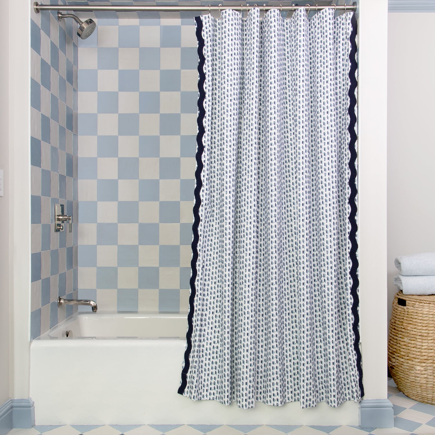 Sky and Navy Blue Poppy Printed shower curtain hanging on rod in front of white tub in bathroom with blue and white tiles