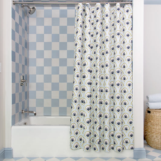 Art Deco Palm Pattern Printed shower curtain hanging on rod in front of white tub in bathroom with blue and white tiles